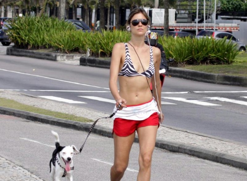 De shortinho, Ellen Jabour caminha com seu cachorro na orla da Barra