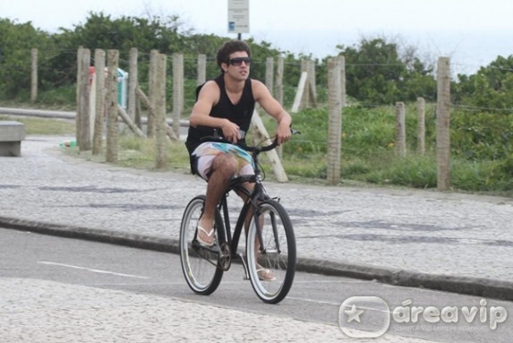 Caio Castro anda de bicicleta na orla da praia