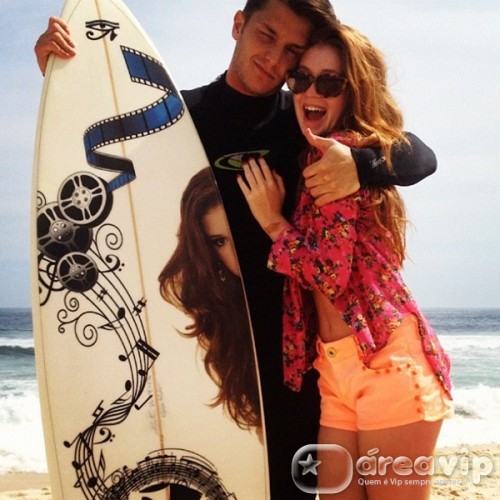 Klebber Toledo posa ao lado da namorada com prancha de surfe com foto dela