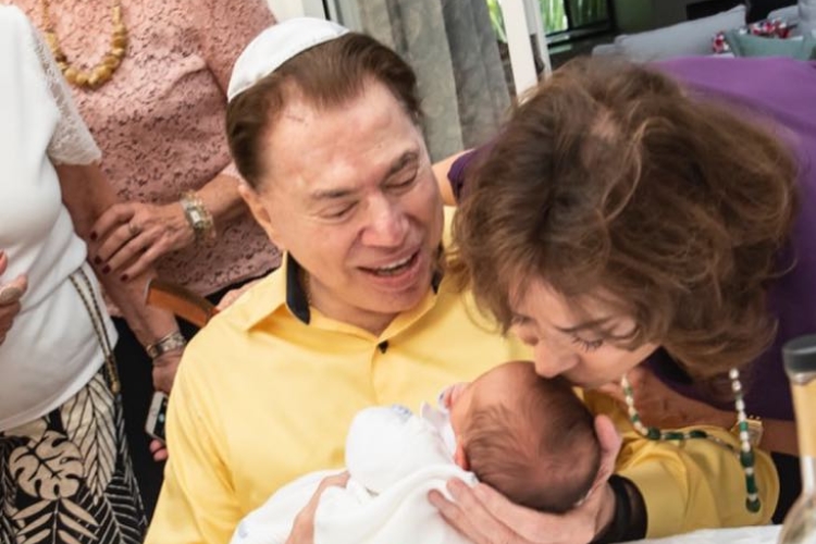 Silvio Santos posa sorridente segurando seu neto, Senor, em momento família