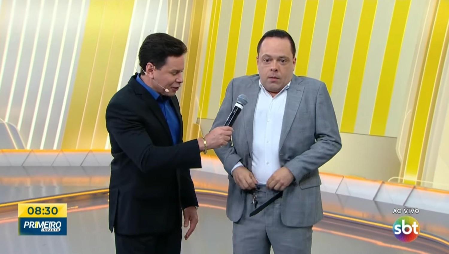 Thiago Gardinali arrumando as calças durante o Primeiro Impacto - Foto: Reprodução/SBT