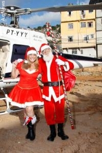 Vestida de Mamãe Noel, Susana Vieira chega na Rocinha de helicóptero